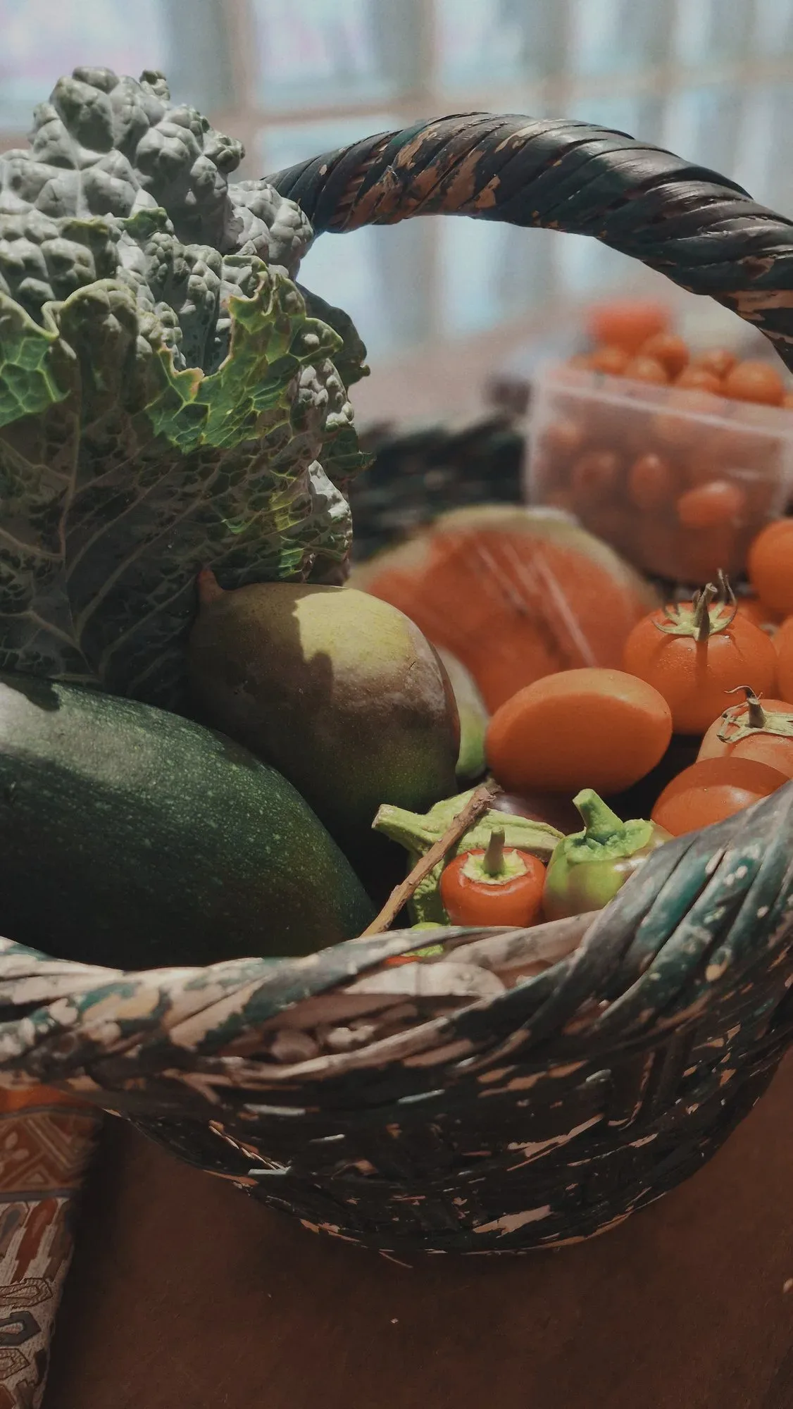 A basket of tomatoes, peppers, courgettes and mango from the finca